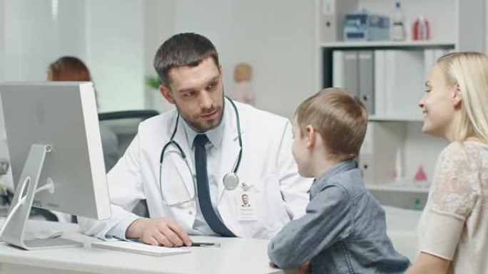 在医生办公室。善良的男医生与小男孩和他的母亲交谈和开玩笑。