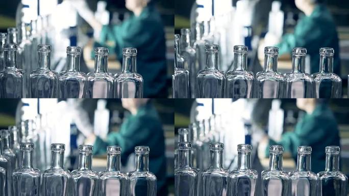 当工厂工人观察过程时，玻璃状瓶子的直线沿输送机移动