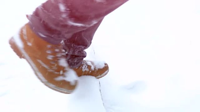 穿着靴子在冬天的风景中行走，冬天在山上行走，克服障碍以慢动作落下的雪