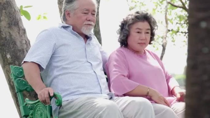 坐在长凳上的高级夫妇看着公园。
