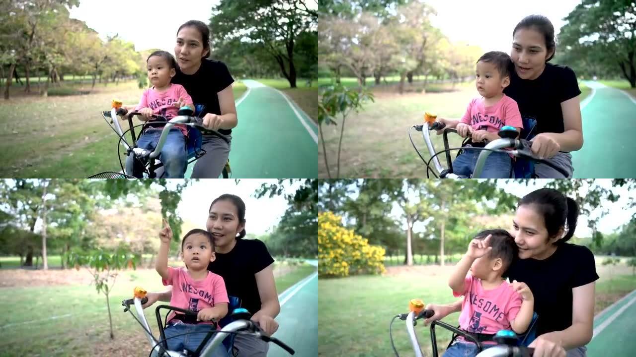 母亲和男婴在公园户外一起骑自行车。