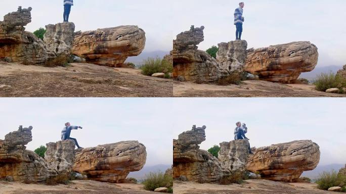 坐在岩石上的人通过双筒望远镜观看4k