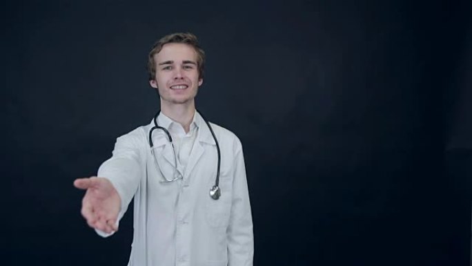 微笑的医生伸出援手，站在黑色背景上。包装照片