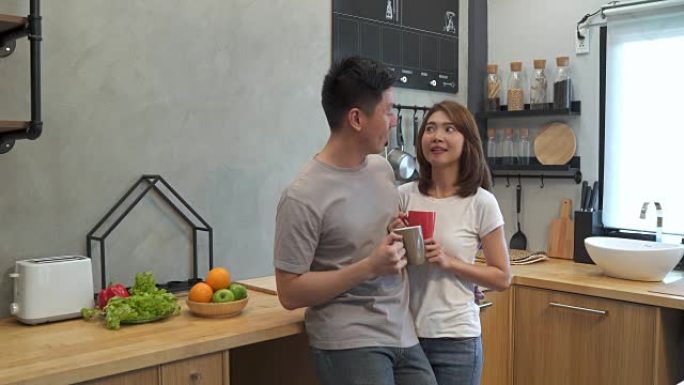 美丽幸福的亚洲夫妇正在厨房里一起喝一杯咖啡。男人和女人一边吃早餐一边聊天。年轻的亚洲夫妇在家里度过浪