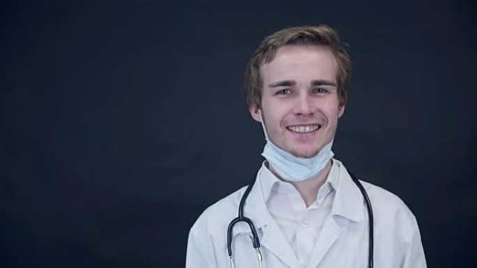 微笑的医生取下医用口罩，看着屏幕。包装照片