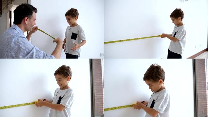 可爱的小男孩在爸爸的帮助下学习如何测量墙壁和使用卷尺