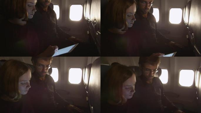 夫妻俩一起坐在飞机上并使用平板电脑。