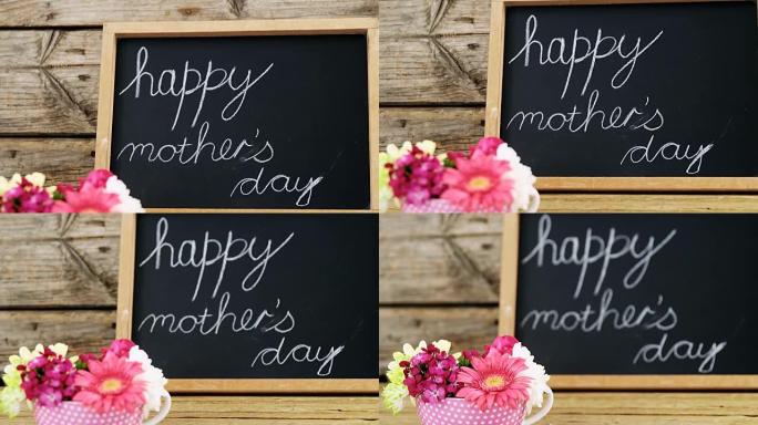 母亲节快乐的文字写在粉笔板上，用一杯鲜花