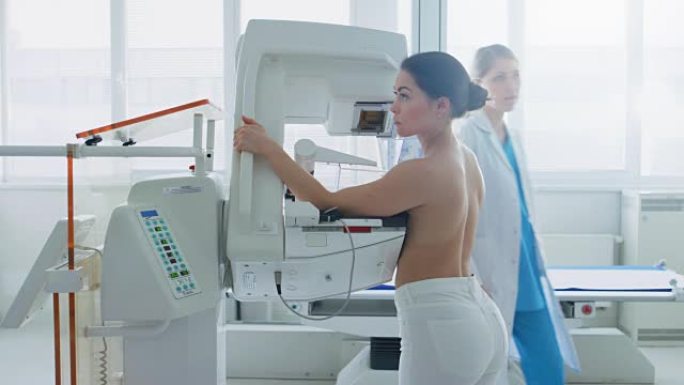 在医院里，正在接受乳房x线筛查的半裸女性病人的侧视图。健康年轻女性进行癌症预防性乳房x线摄影扫描。拥