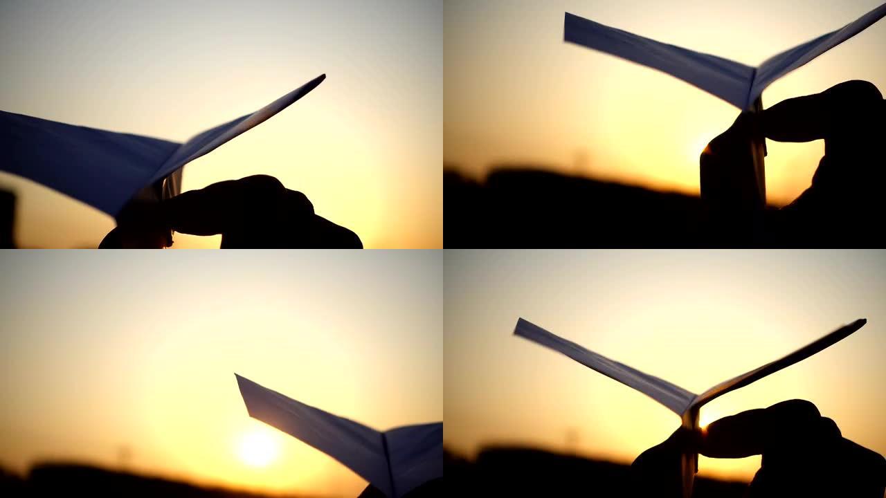 日落时手持纸飞机