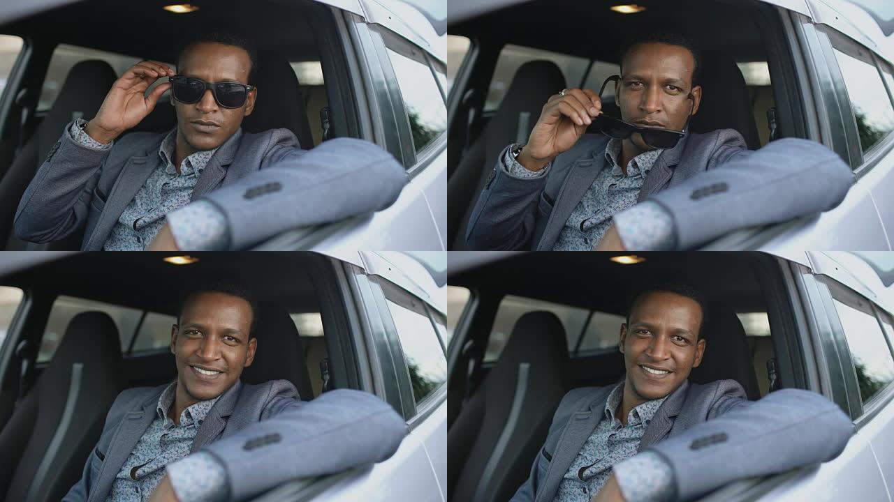 坐在车内的认真商人的肖像戴上墨镜，在户外对着相机微笑