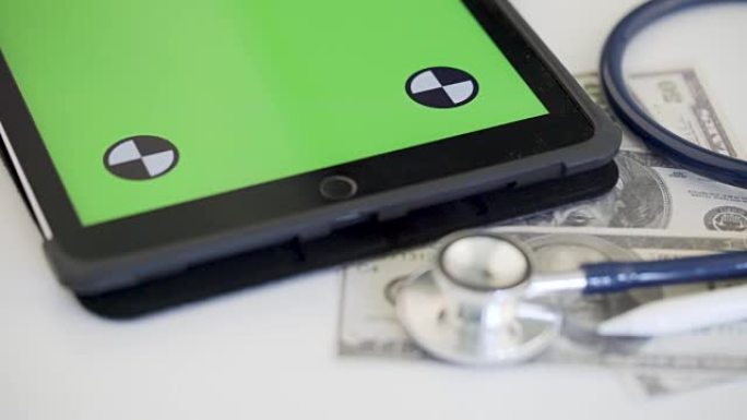 绿色屏幕上的钱和平板电脑听诊器的4k镜头。医疗保健概念
