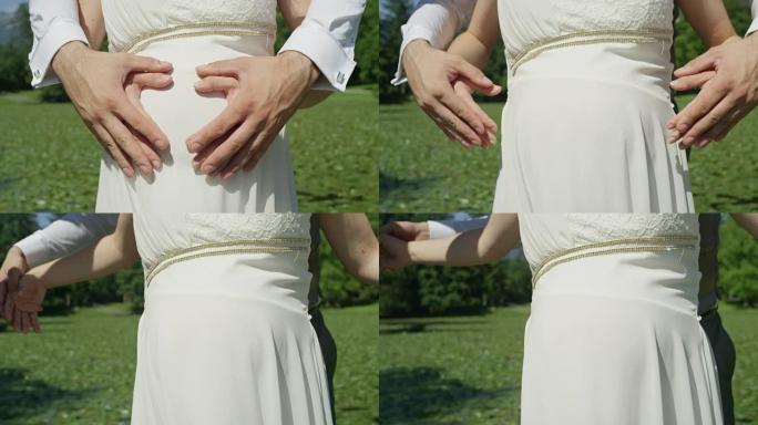 慢动作特写无法辨认的夫妇在怀孕的腹部形成心形