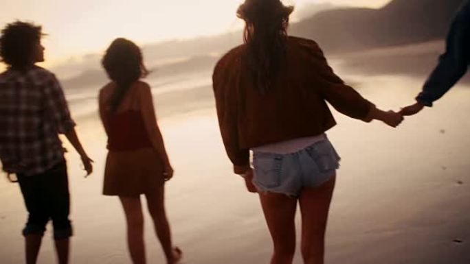 青少年朋友在日落时在海滩上散步