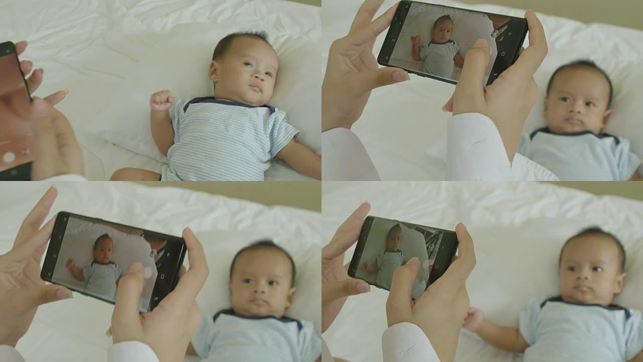 年轻的亚洲母亲用智能手机给她刚出生的孩子拍照。