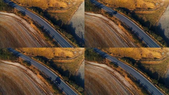 自上而下的空中拍摄乡间小路，耕地和道路两侧。日落多彩的场景。