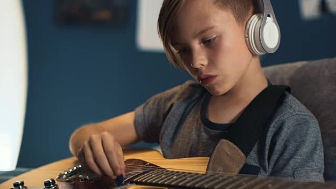 戴着耳机的男孩用吉他学习歌曲