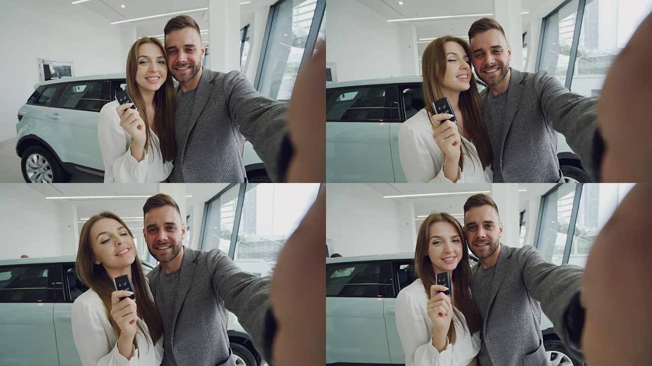 有吸引力的年轻夫妇在购买新车后，在现代汽车陈列室用车钥匙自拍。他们看着相机，亲吻和微笑。