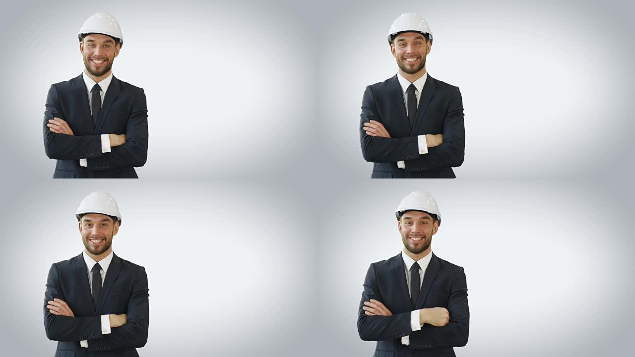 一个商人戴着安全帽，微笑着双手交叉。在白色背景上拍摄。