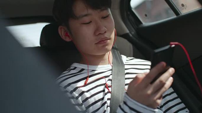 亚洲青少年在汽车上的智能手机上听音乐
