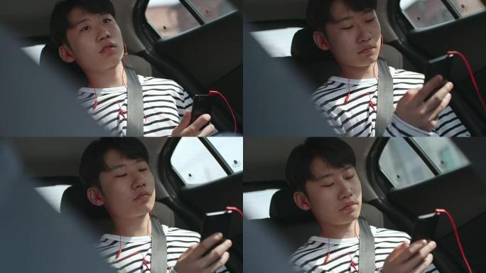 亚洲青少年在汽车上的智能手机上听音乐