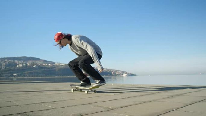 慢动作dop: 滑板手在混凝土海岸跳跃并进行翻转技巧