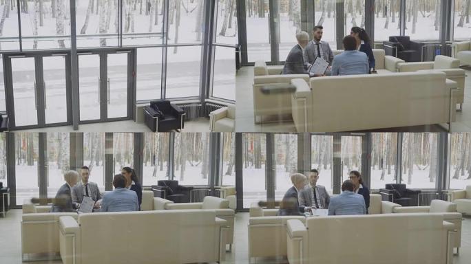 从电梯下移到一群商务人士的观点同事坐在现代商务中心大厅的沙发上讨论财务图表