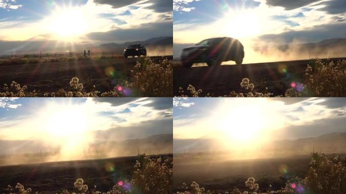 慢动作: 黑色SUV汽车在土路上行驶，在金色的夕阳上扬起灰尘