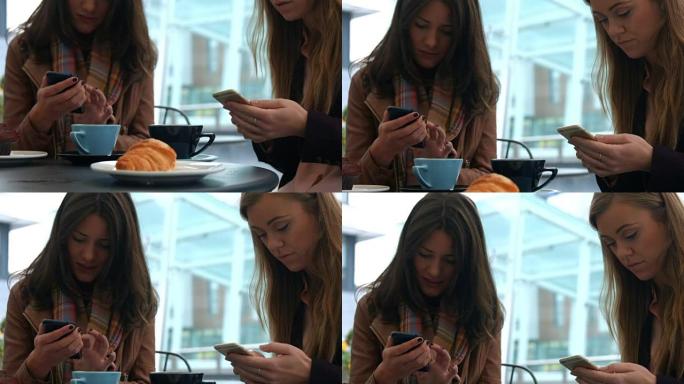 漂亮的朋友在咖啡馆里用手机喝咖啡