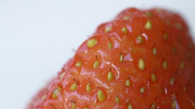 特写: 甜红色草莓果实中的小种子的细节。在浆果上下雨
