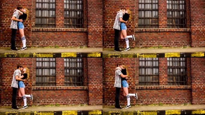一对十几岁的情侣在旧工业大楼前接吻