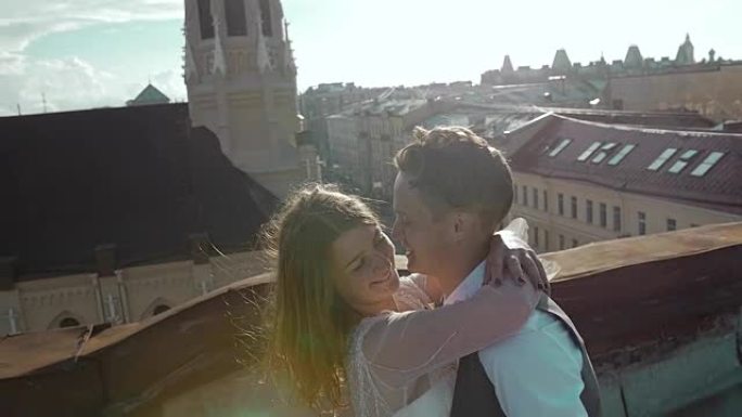 年轻快乐美丽的时尚夫妇在日落时轻轻地拥抱在屋顶上