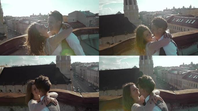 年轻快乐美丽的时尚夫妇在日落时轻轻地拥抱在屋顶上