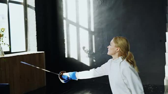年轻集中的击剑女子在室内工作室训练击剑攻击练习