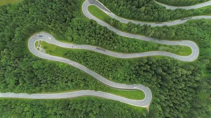 空中: 沿着风景秀丽的弯曲蛇形道路行驶的汽车，急转弯