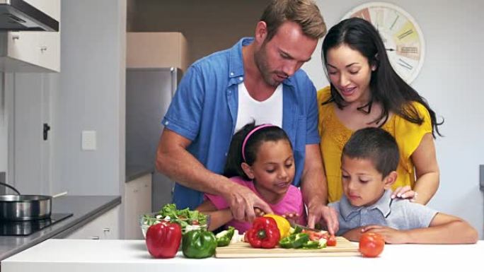 可爱的家庭在厨房里切蔬菜