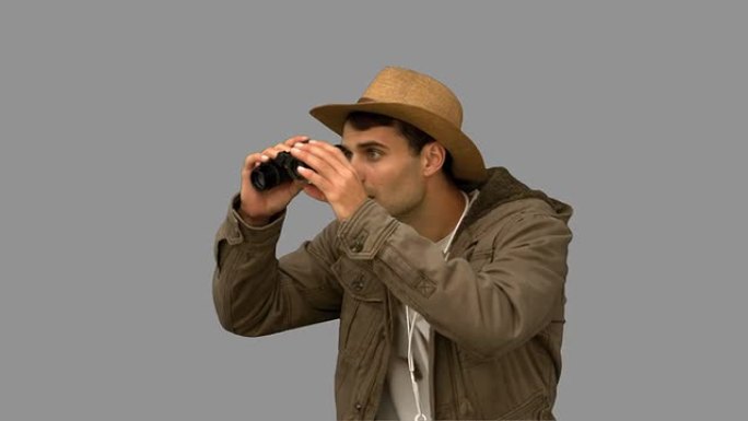 男子在灰色屏幕上使用双筒望远镜穿着外套