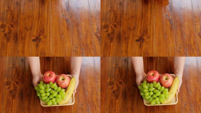 双手在木桌上拿着水果