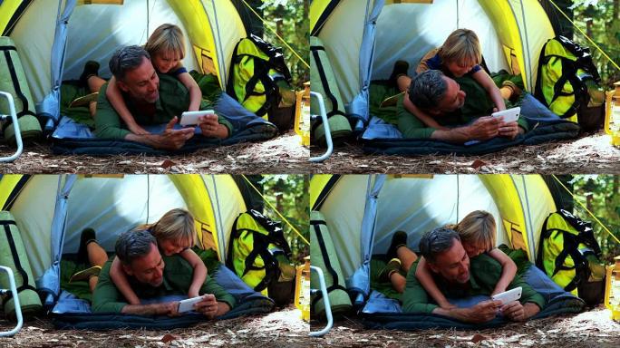 父子俩在帐篷外使用手机