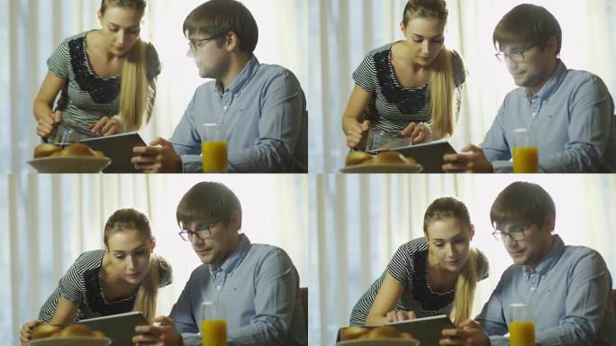 夫妇吃早餐。男人正在平板电脑上阅读新闻。在4k (UHD) 的红色电影相机上拍摄。