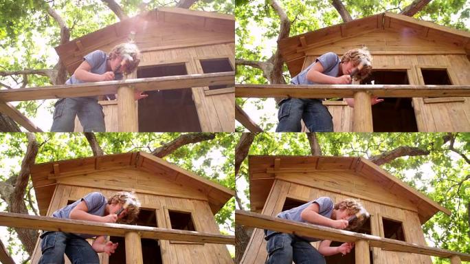 男孩用锤子和钉子修理他的木制树屋