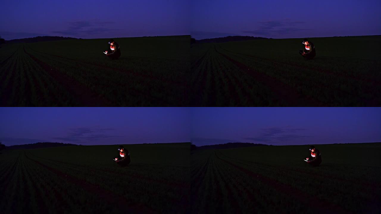 农民晚上在黑暗的麦田里使用数字平板电脑，实时
