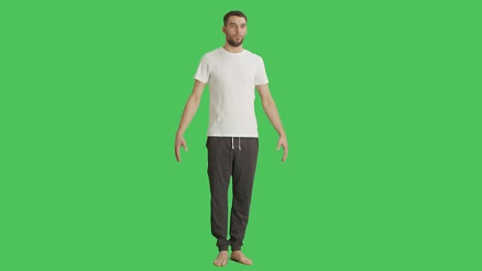 一个穿着t恤和运动裤的赤脚男子的长镜头，而相机在他周围旋转。在绿屏背景上拍摄。