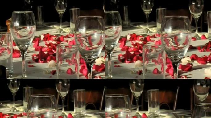 桌上的猩红玫瑰花瓣和玻璃杯