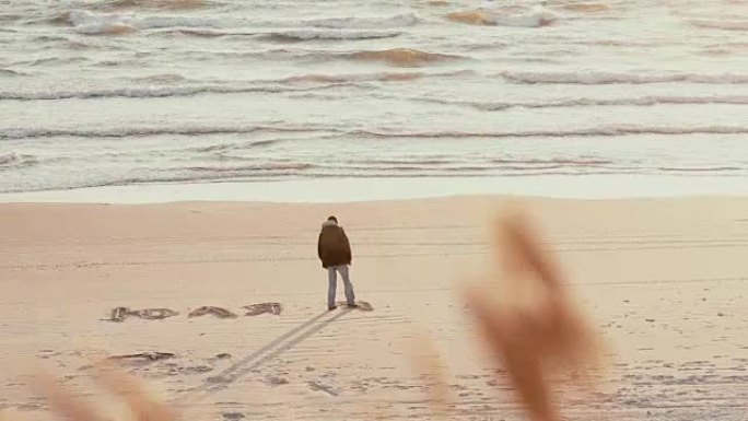 一个用脚在美丽海滩的沙滩上用俄语写朱莉娅的家伙的远景