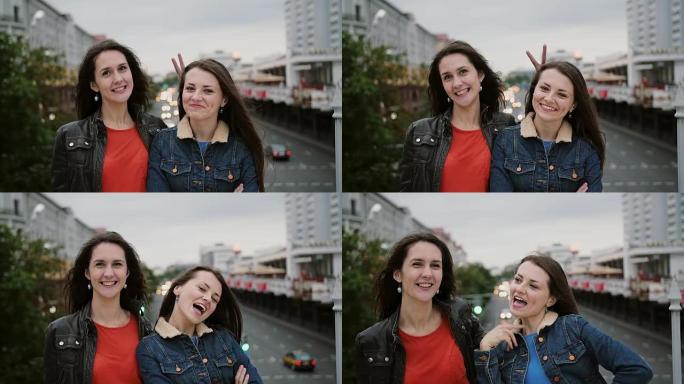 两个漂亮的女孩站在桥上，微笑着，笑着看着镜头。风吹他们长发