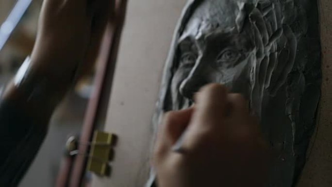 雕塑家在艺术工作室的画布上创作女性脸部雕塑的特写