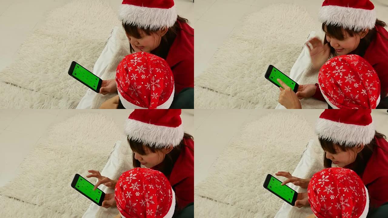 女人的手使用带有绿色屏幕的智能手机进行圣诞节活动