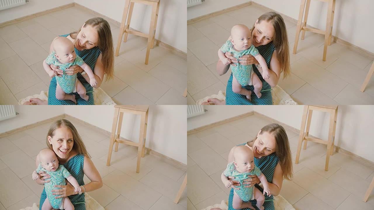 年轻的母亲抱着她的宝贝，对着他微笑，坐在厨房地板上笑着。慢动作