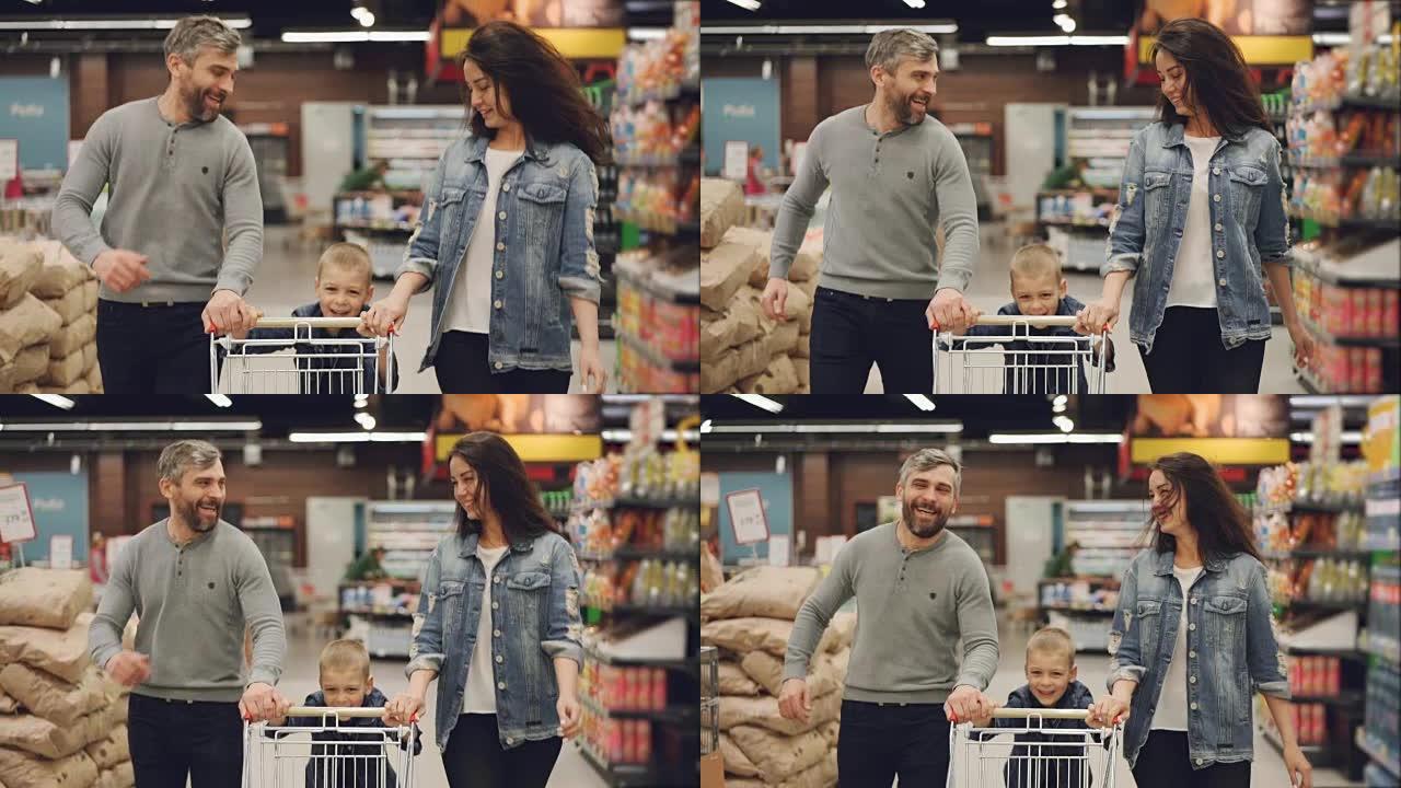 快乐的人的慢动作幸福的家庭在食品商店里用购物车和笑声奔跑，男孩正在推着手推车，他的父母正在帮助他。